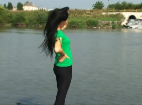 Adria is taking a dip in the river wearing black leggings and a green t-shirt.